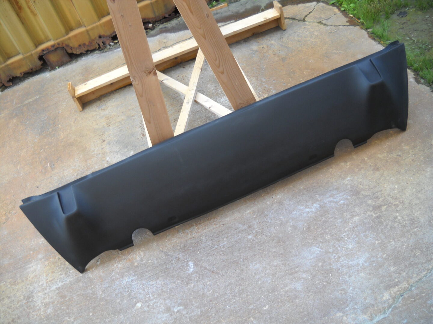 Black car rear bumper cover on concrete